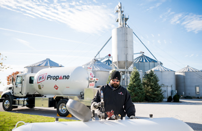 driver filling  propane tank in front of grain bins